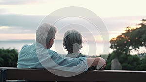 Head shot close up portrait happy grey haired middle aged woman with older husband, enjoying sitting on bench at park. Bonding