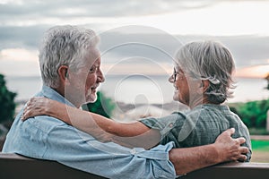 Head shot close up portrait happy grey haired middle aged woman snuggling to smiling older husband, enjoying sitting on bench at