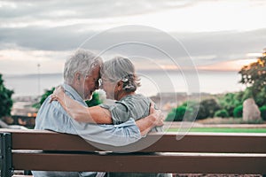 Head shot close up portrait happy grey haired middle aged woman snuggling to smiling older husband, enjoying sitting on bench at