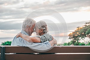 Head shot close up portrait happy grey haired middle aged woman snuggling to smiling older husband, enjoying sitting on bench at