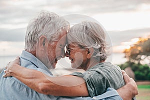 Head shot close up portrait happy grey haired middle aged woman snuggling to smiling older husband, enjoying sitting on bench at