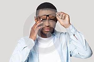 Head shot stressed African American man in glasses touching eyelids photo