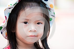 Head shot. Cute girl showed a sad expression. Asian child is in a bad mood.