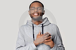 Head shot grateful African American man holding hands on chest photo