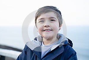 Head shot Healhty kid smiling face with blurry background, Portrait Happy boy standing outside with bright light on Spring or