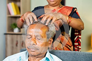 head shot of Old senior man enjoying head massage from wife at home - concept of relaxation, headache and wellbeing