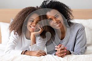 Head shot portrait of African American mother and daughter on bed