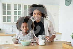 Head shot portrait African American mother with daughter cooking pancakes