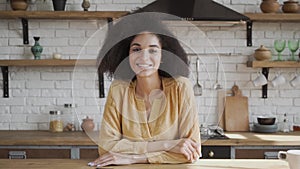 Head shot portrait attractive African American biracial woman at kitchen, happy young female smiling, look at camera