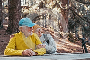 Head shot portrait close up of cute couple of old middle age people having fun and enjoying together in the forest of the mountain