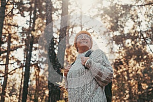 Head shot portrait close up of middle age caucasian woman walking and enjoying nature in the middle of trees in forest. Old mature