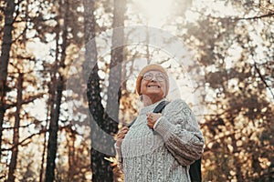 Head shot portrait close up of middle age caucasian woman walking and enjoying nature in the middle of trees in forest. Old mature