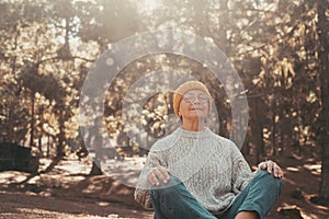 Head shot portrait close up of one middle age old woman resting and relaxing doing yoga in the forest of mountain in the nature.