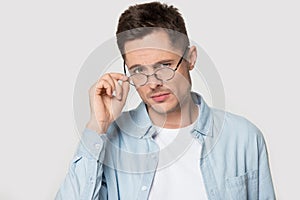 Head shot portrait distrustful man lowering eyeglasses looking at camera photo