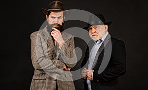 Head shot portrait of elderly mature dad and grownup son. Two male generations family. Men in hat on dark studio