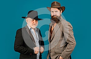 Head shot portrait of elderly mature senior dad and grownup son. Two male generations family. Men in hat. Men in