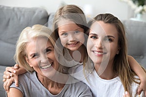 Happy laughing granddaughter mother and grandmother looking at camera