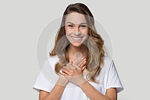 Head shot portrait grateful young woman holding hands on chest