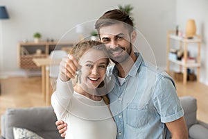 Head shot portrait of happy couple in love holding keys, hugging