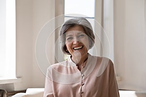 Head shot portrait of happy middle-aged grey-haired woman