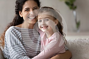 Head shot portrait happy mother with little daughter hugging