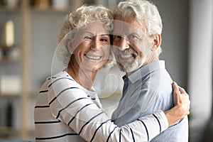 Head shot portrait happy older couple hugging, looking at camera