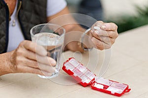 Head shot portrait happy woman holds pill glass of water, takes daily medicine vitamin D, omega 3 supplements, skin hair