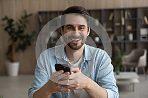 Head shot portrait laughing man holding smartphone, having fun