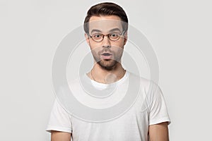 Head shot portrait millennial surprised man looking at camera.