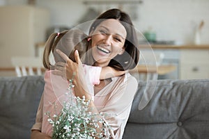 Head shot portrait mother hugging little daughter, thanking for flowers