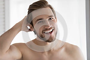 Head shot portrait overjoyed satisfied young man touching hair