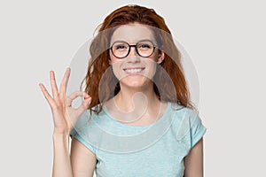 Head shot portrait young smiling woman showing okey gesture.