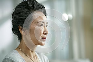 Head shot portrait of a sad asian senior woman