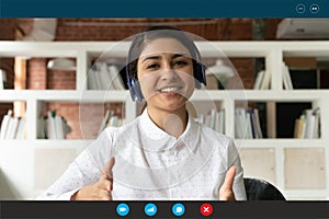 Head shot portrait screen view smiling Indian woman wearing headphones
