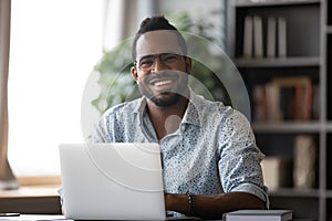Head shot portrait smiling African American businessman with laptop
