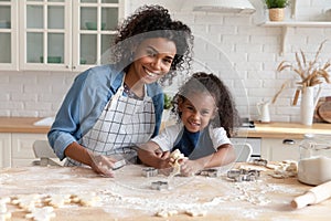 Head shot portrait smiling African American mother with daughter cooking