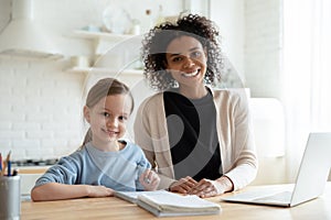Head shot portrait smiling African American mother with daughter studying