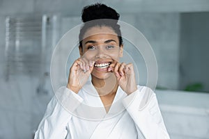 Head shot portrait smiling African American woman using dental floss