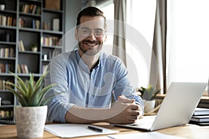 Head shot portrait smiling businessman wearing glasses sitting at desk