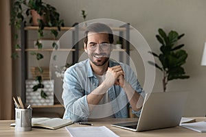 Head shot portrait smiling businessman wearing glasses sitting at table