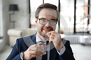 Head shot portrait smiling businessman wearing glasses taking meds photo