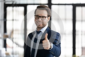 Head shot portrait smiling businessman wearing suit showing thumb up