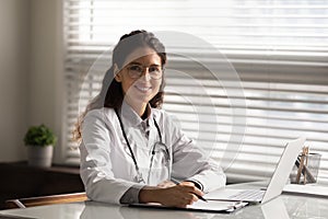 Head shot portrait smiling female doctor filling medical documents