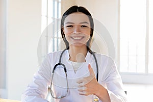 Head shot portrait smiling female doctor showing thumb up