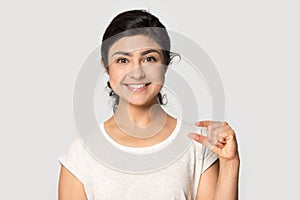 Head shot portrait smiling Indian girl showing little size gesture