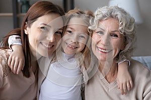 Head shot portrait smiling little girl hugging mother and grandmother