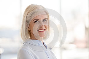 Head shot portrait smiling mature businesswoman look at camera