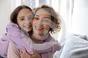 Head shot portrait smiling pretty teenage daughter hugging mother