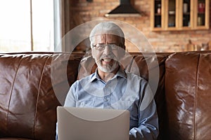 Head shot portrait smiling senior man in glasses using laptop