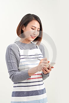 Head shot portrait of smiling waitress wearing black apron ready to take customer order, attractive woman with notebook and pen in